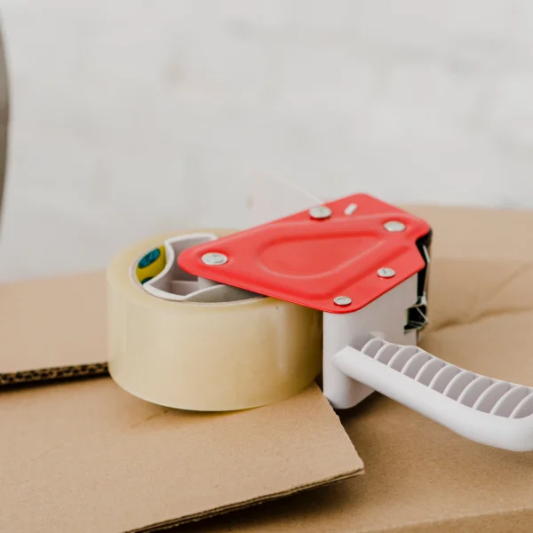 Un distributeur de ruban adhésif posé sur une boîte en carton, illustrant l'emballage sécuritaire.