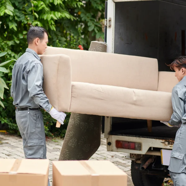 Deux hommes transportent un canapé, illustrant un emballage sécuritaire pour le déménagement.